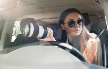 private detective with camera spying from car