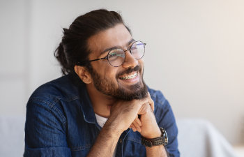 happy cheerful young man with beard with glasses and braces on teeth